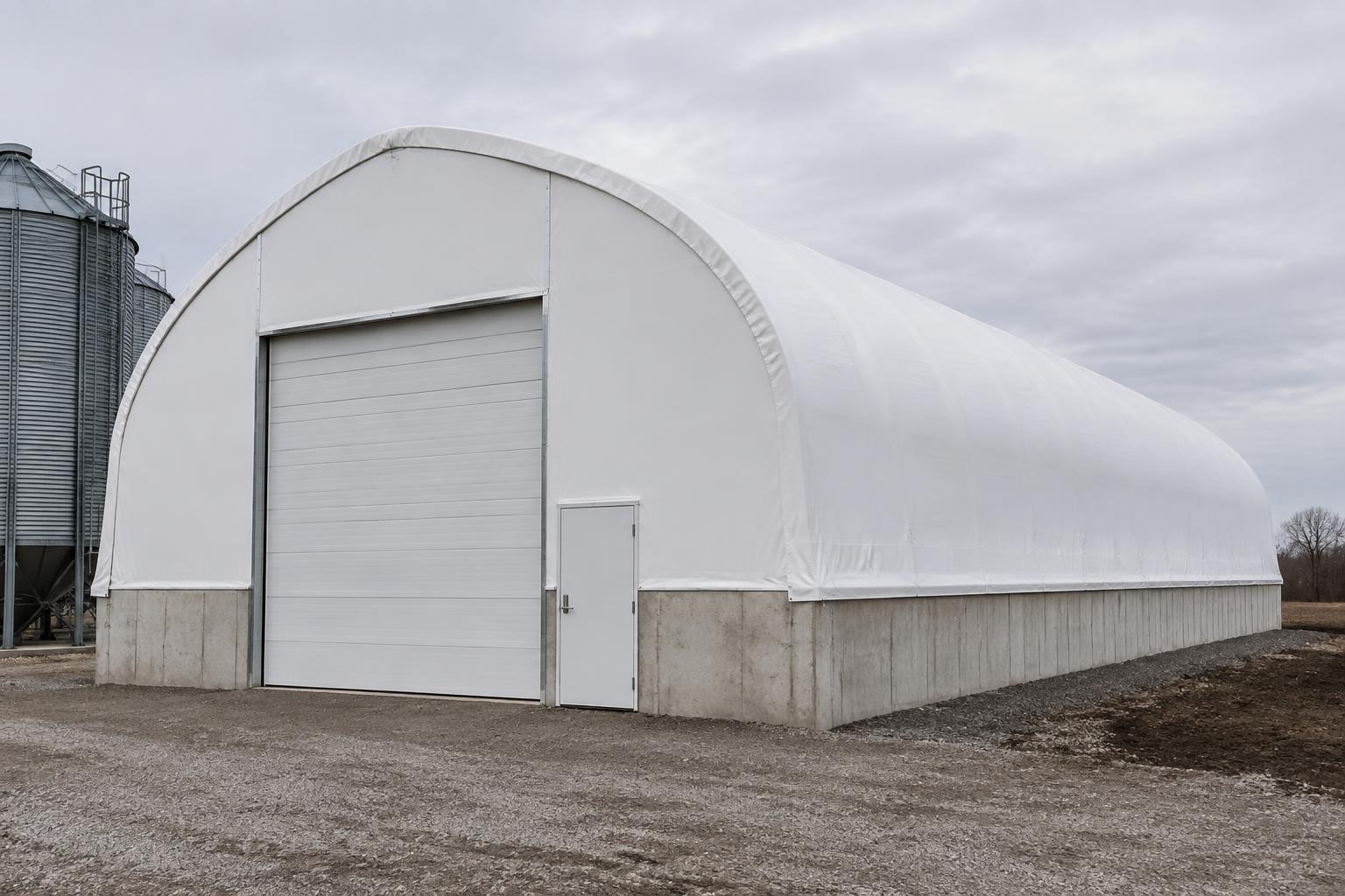 Insulated fabric cold storage building on a poured concrete stem wall with an insulated sectional door