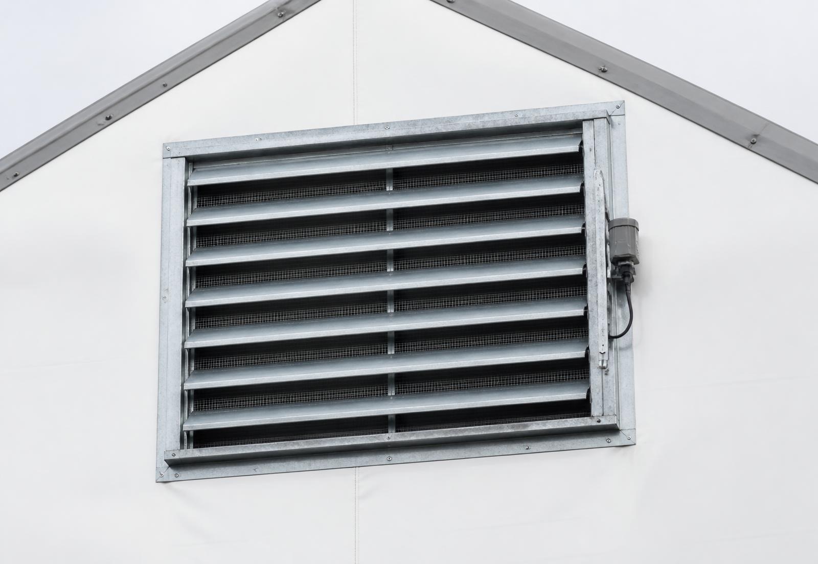 Motorized galvanized gable louver with insect screen mounted high on the gable end of a MegaDome fabric building