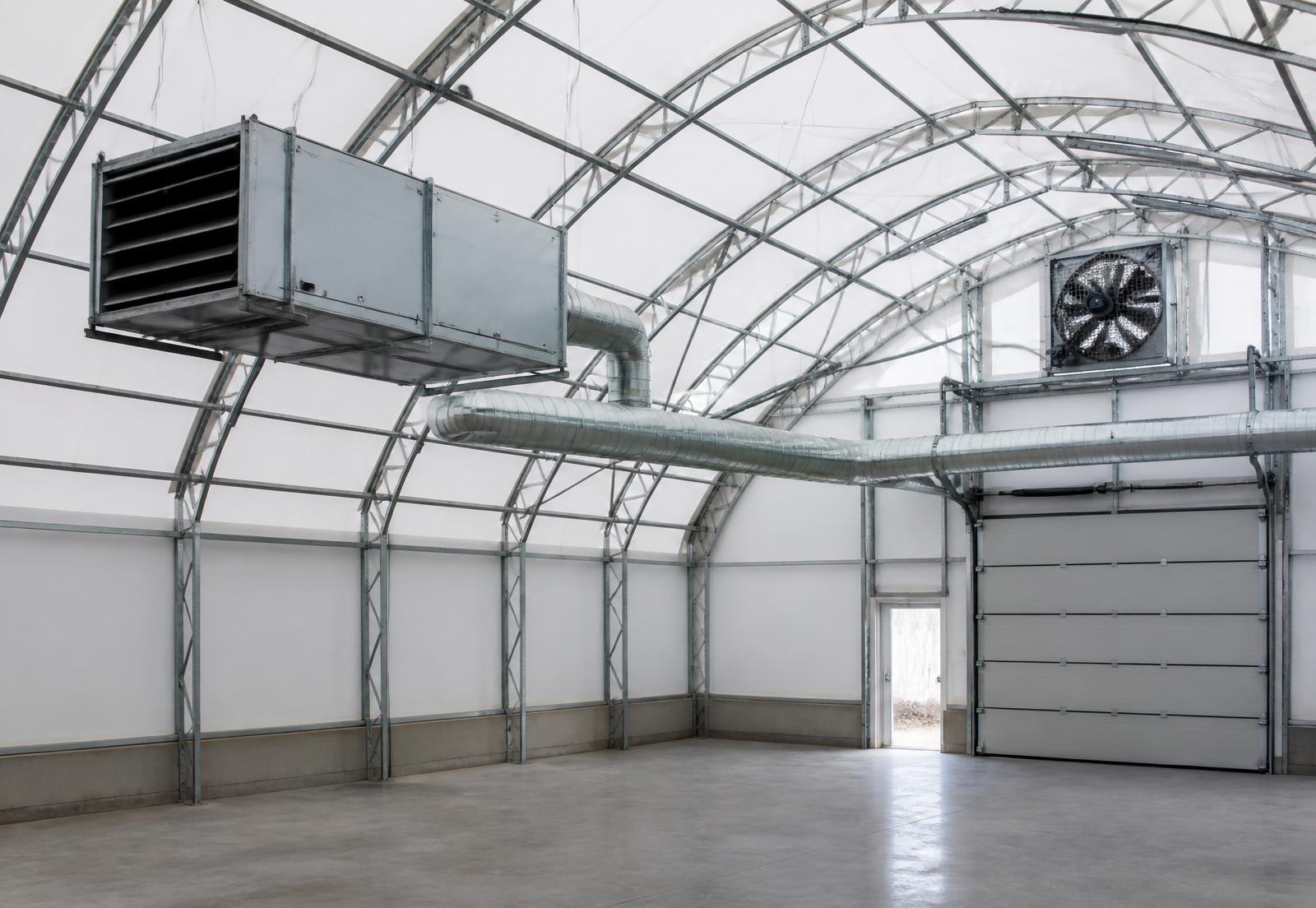 Interior of an industrial MegaDome fabric building with overhead make-up air heater, spiral ductwork and high-mounted exhaust fan