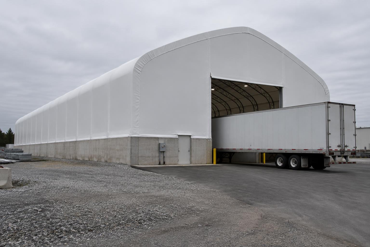 Fabric warehouse building on a poured concrete stem wall with a trailer at the open end-wall door